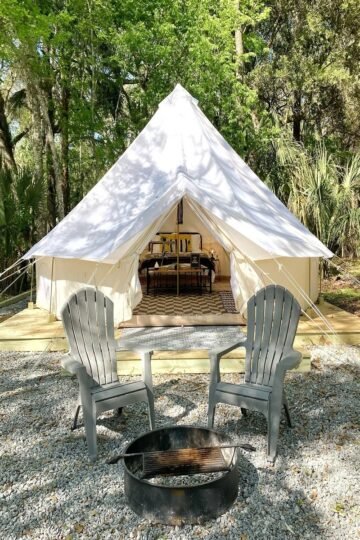 Cozy glamping tent setup with chairs and fire pit in the forest, perfect for Vermont State Park Camping experience.