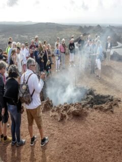 Group of tourists watching geothermal activity during Volcano Tours Lanzarote in Timanfaya National Park