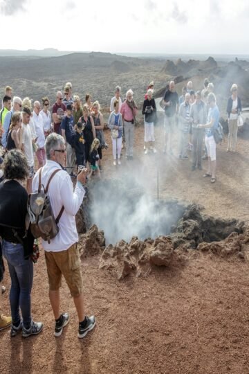 Group of tourists watching geothermal activity during Volcano Tours Lanzarote in Timanfaya National Park