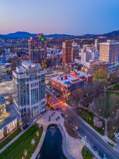 Aerial view of downtown Huntsville at sunset, showcasing city lights, hotels, and parks near top fun things to do in Huntsville.